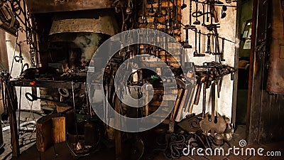 Interior of Blacksmith forge with tools hanging on wall and anvil and hammer ready to be used. Furnace formant Stock Photo