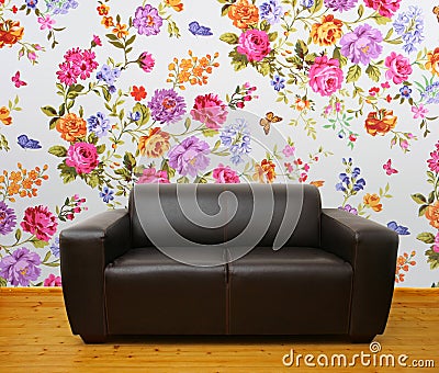 Interior with brown leather couch against floral wall Stock Photo