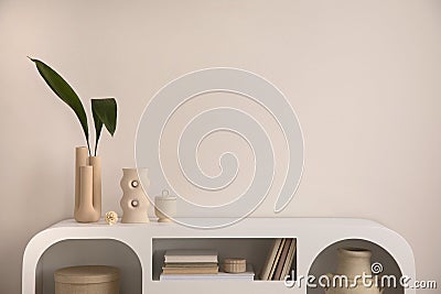 Interior design of aesthetic and elegant room with copy space, modern white commode, books, decoration, vase with leaf and Stock Photo
