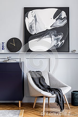 Interior design of living room with stylish navy blue commode, grey armchair, pillow, black clock, mock up modern paintings. Stock Photo