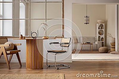 Interior design of open space interior with round table, rattan chair, window, vase with dried flowers, modular sofa, wooden Stock Photo