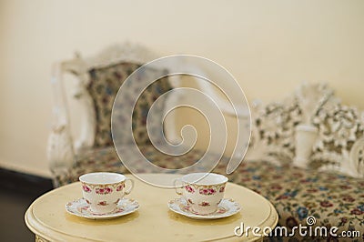 Interior of an elegant room decorated with a vintage couch in front of two elaborate teacups Stock Photo