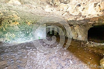 Interior of an empty cave, walls with uneven texture and cracks, concrete supports or columns in background Stock Photo