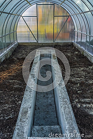 Interior of empty greenhouse before spring with concrete walls Stock Photo