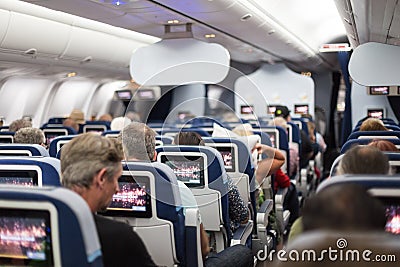 Interior of large commercial airplane with passengers on seats waiting to taik off. Editorial Stock Photo