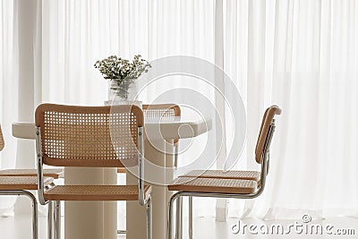 Interior of light dining room with white table, rattan chairs. Japandi interior concept. Stock Photo