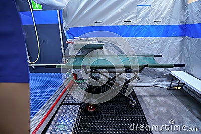 Interior of mobile plastic decontamination shower tent with small steel wash basin, mobile stretcher near Stock Photo