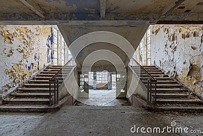 Interior of old abandoned school with symmetric stairways and weathered walls Stock Photo