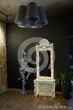 Interior of the room. A large mirror with a garland, and a huge gray chandelier. Stock Photo