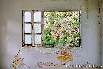 Interior of a ruined house with old, dirty and cracked white wall and a broken window frame Stock Photo