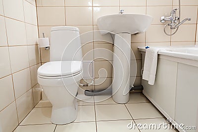 Interior of simple half bathroom with toilet, sink and bath with shower, white sanitary ware Stock Photo