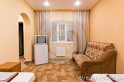 The interior of a small room with sofa bed and two single beds, window, TV and fridge Stock Photo