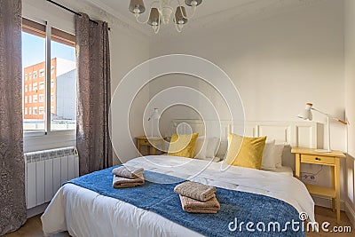 Interior of touristic bedroom with window. Yellow pillows on bed with towels. An apartment ready for booking by tourists Stock Photo