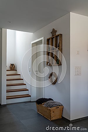 Interior view of an elegant hallway and stairs with black tile floor and white plaster walls and wooden furniture and decorative Stock Photo