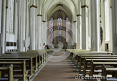 Interior view of a large bright church and stained glass with empty benches. Stock Photo