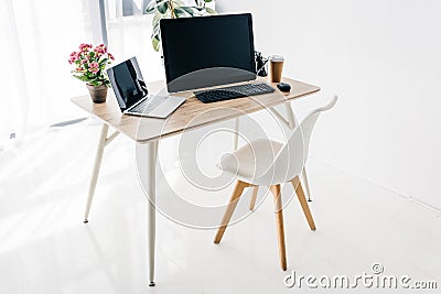 interior of workplace with chair, flowers, coffee, stationery, laptop and computer Stock Photo