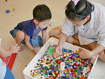 Interlocking plastic bricks in mother`s hands being built with help from her little baby Stock Photo