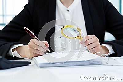 Internal audit concept - woman with magnifying glass inspecting Stock Photo