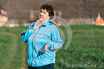 International Day of Older Persons. Portrait of an elderly thoughtful woman holding a cellphone in her hand. Outdoor Stock Photo