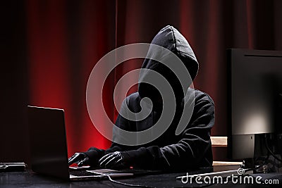 International hacker in black pullover and black mask trying to hack government on a black and red background. Cyber crime . Stock Photo