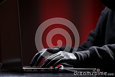 International hacker in black pullover and black mask trying to hack government on a black and red background. Cyber crime . Stock Photo