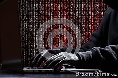 International hacker in black pullover and black mask trying to hack government on a black and red background. Cyber crime . Stock Photo