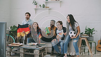 International young friends football match on TV together at home. Most of them happy about German team winning but Stock Photo