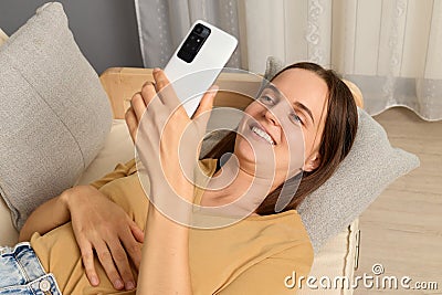 Internet browsing. Online searching. Social app. Web addiction. Beautiful smiling joyful brown haired woman wearing beige T-shirt Stock Photo