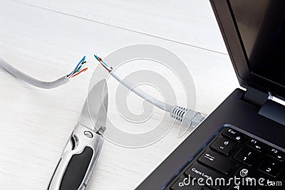 Internet cable, laptop and pocket knife Stock Photo