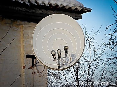 Internet communication and TV satellite dish installed on the roof of the house at green trees background. Stock Photo