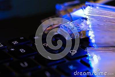 Internet switches on laptop computer keyboard, glowing optical fibres close up Stock Photo