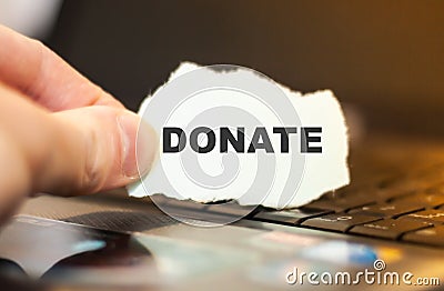 Internet user holds torn paper with the word DONATE Stock Photo