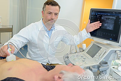 Internist consulting elderly patient performing ultrasound examination Stock Photo