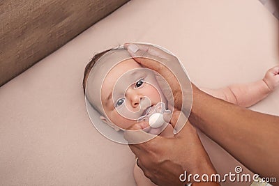Interracial father calming his baby with a pacifier Stock Photo