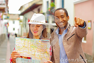 Interracial happy couple wearing casual clothes in urban envrionment, interacting and looking at map Stock Photo