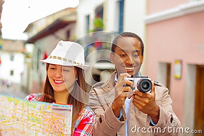 Interracial happy couple wearing casual clothes in urban envrionment, interacting and looking at map Stock Photo