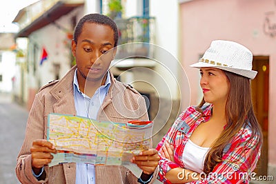 Interracial happy couple wearing casual clothes in urban envrionment, interacting and looking at map Stock Photo