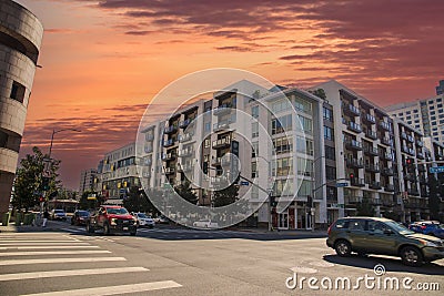 An intersection at Grand Ave and Olympic Blvd with a white and brown apartment building, cars driving and people walking Editorial Stock Photo