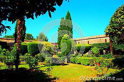 Intimate view of the San Giovanni in Venere gardens with red roses, green hedges and a crucifix Stock Photo