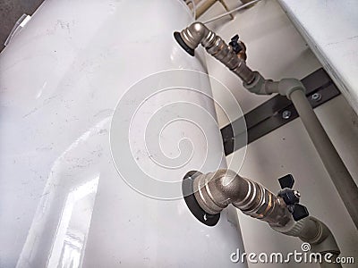 An intricate array of pipes and valves behind the scenes. Complex Plumbing Configuration Behind a Public Restroom Wall Stock Photo