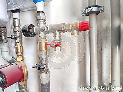 An intricate array of pipes and valves behind the scenes. Complex Plumbing Configuration Behind a Public Restroom Wall Stock Photo