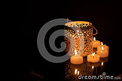 Intrincate metal candle holder with a lighting scented candle are displayed on the blak stone table in the dark living room of the Stock Photo