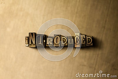 INTRODUCED - close-up of grungy vintage typeset word on metal backdrop Cartoon Illustration