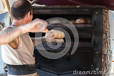 Introducing artisan baker dough in the oven Editorial Stock Photo