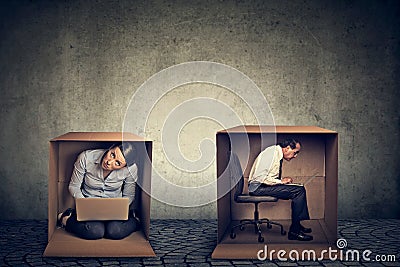 Introverts. Man and woman sitting inside boxes working on laptop Stock Photo