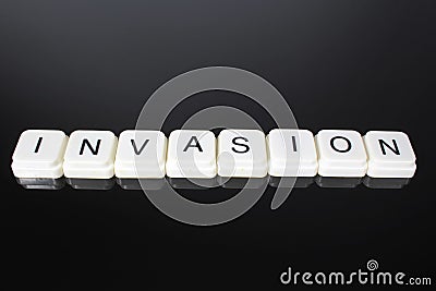 Invasion text word title caption label cover backdrop background. Alphabet letter toy blocks on black reflective Stock Photo