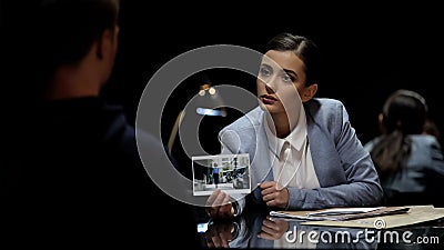 Investigation officer showing murder suspect victim photo, police interrogation Stock Photo