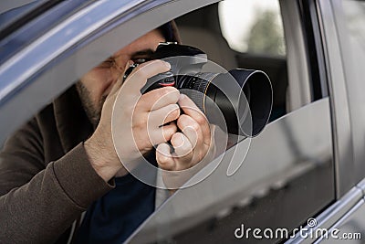 Investigator or private detective, reporter or paparazzi sitting in car and taking photo with professional camera Stock Photo