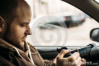 Investigator or private detective or reporter or paparazzi sitting in car and taking photo with professional camera Stock Photo