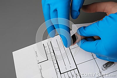 Investigator taking fingerprints of suspect at table. Criminal expertise Stock Photo